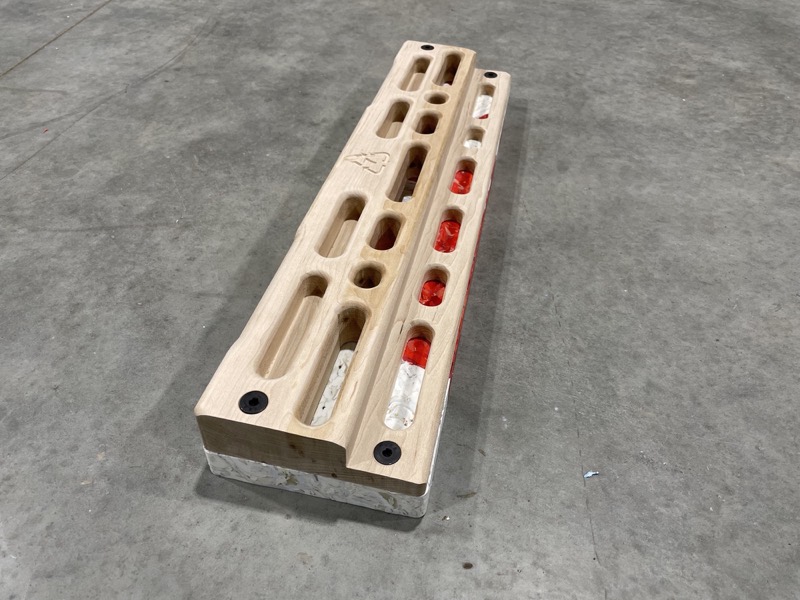 An alternate hangboard design: wood over a pressed recycled-HDPE base, with red and white recycled-plastic grip inserts.